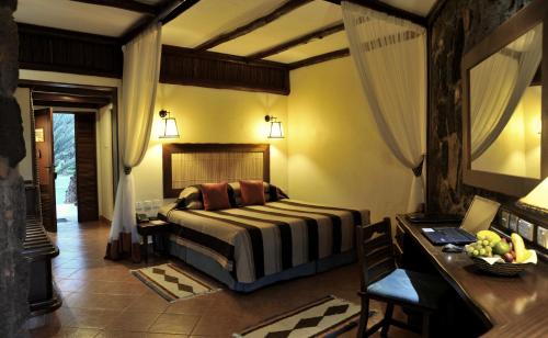 - une chambre avec un lit et un bureau dans l'établissement Kilaguni Serena Safari Lodge, à Tsavo