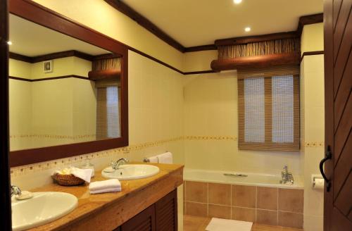 uma casa de banho com 2 lavatórios, uma banheira e um espelho. em Kilaguni Serena Safari Lodge em Tsavo