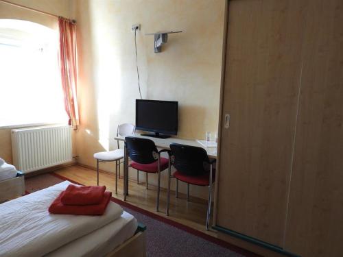 Schlafzimmer mit einem Schreibtisch mit Stühlen und einem TV in der Unterkunft Gasthof Schlosswirt in Klagenfurt am Wörthersee