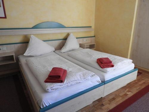 a bed with two red towels on top of it at Gasthof Schlosswirt in Klagenfurt