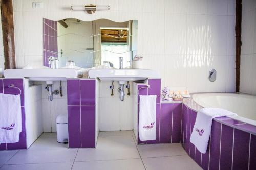 Baño blanco y púrpura con 2 lavabos y bañera en TshiBerry Bed & Breakfast en Phokeng