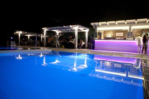 a swimming pool at night with people standing around it at Club Esse Sporting in Stintino