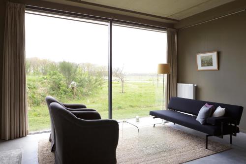 a living room with a couch and a large window at Landhuis Hotel Rikus in Eext