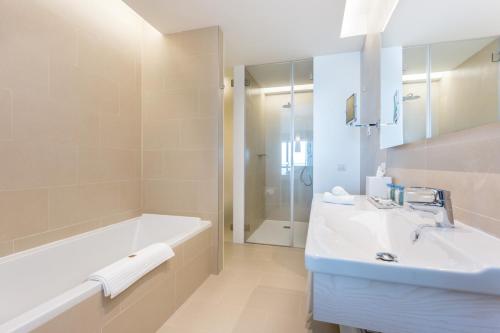 a white bathroom with a tub and a sink at Palmares Beach House Hotel - Adults Only in Lagos
