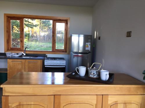 a kitchen with a wooden table with two mugs on it at Cabañas Posadas De Coyhaique in Coihaique