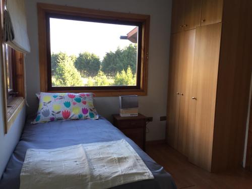 a small bedroom with a bed and a window at Cabañas Posadas De Coyhaique in Coihaique