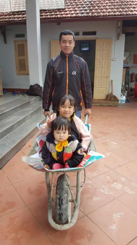a man and two children sitting on a wheelbarrow at Huy Trung Homestay in Bắc Hà