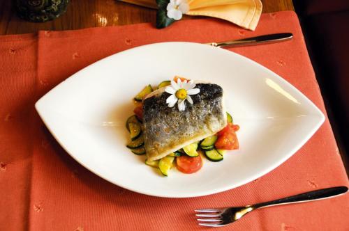 a white plate with a piece of fish and vegetables at Hotel Bergkristall in Mallnitz