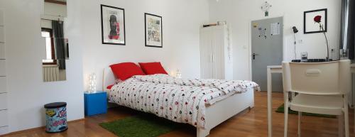 a bedroom with a bed with red pillows and a desk at Apartments Garden Zagreb in Zagreb