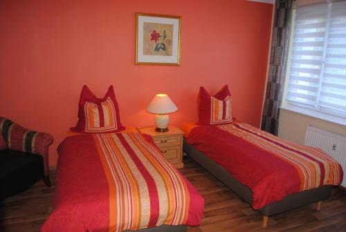 two beds in a room with orange walls at Südwindappartement in Zwenkau