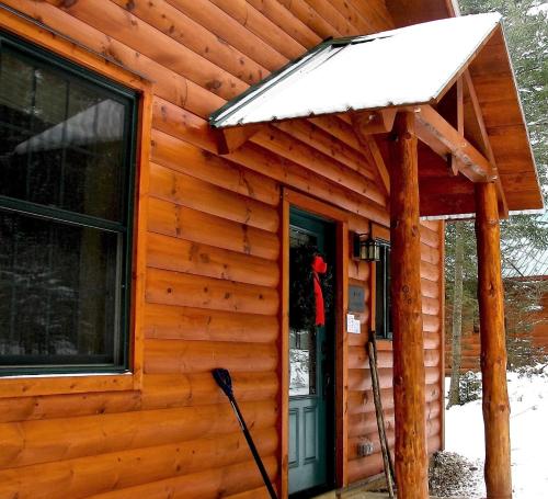 a front door of a log cabin with a snow covered roof at Robert Frost Mountain Cabins in Middlebury