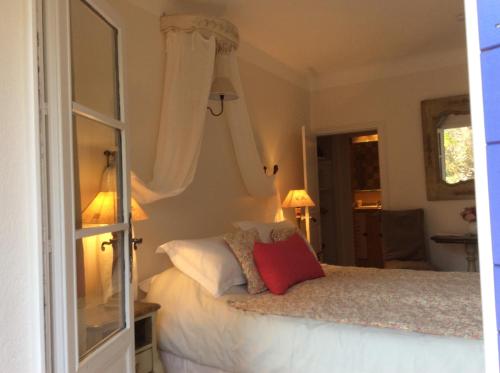 a bedroom with a bed with white sheets and a red pillow at Clos des Iris in Moustiers-Sainte-Marie