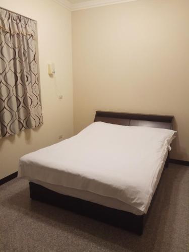 a bedroom with a white bed with a window at Nature House in Wanli