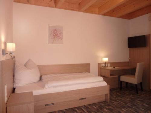 Dormitorio con cama, escritorio y TV en Gästehaus Lodermeier, en Bad Abbach