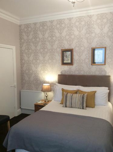 a bedroom with a large bed and a wall at The Westbourne Guest House in Llandudno