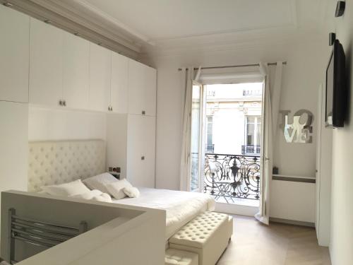 een witte slaapkamer met een bed en een balkon bij Luxe Apartment 165m2 8pers Victor Hugo trocadero foch Champs Elysées in Parijs