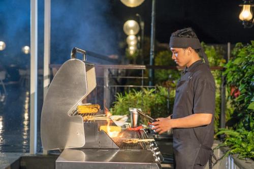 a man cooking food on top of a grill at Jambuluwuk Oceano Seminyak Hotel in Seminyak