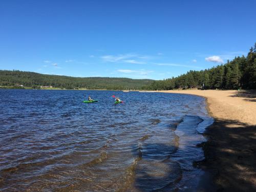 two people in kayaks on a lake next to a beach at Ljusdals Camping in Ljusdal