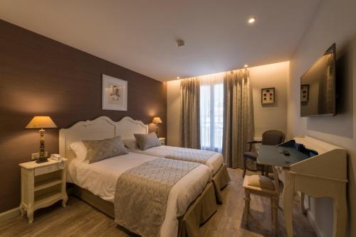 une chambre d'hôtel avec un lit, un bureau et une fenêtre dans l'établissement Nouvel Hôtel du Commerce, à Castellane