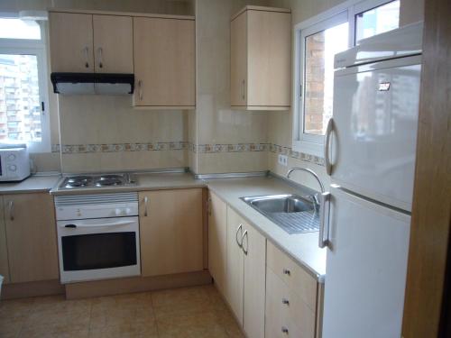 a kitchen with a white refrigerator and a sink at Eden Park - Fincas Arena in Benidorm