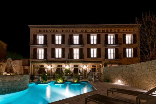 un hôtel avec une piscine en face d'un bâtiment dans l'établissement Nouvel Hôtel du Commerce, à Castellane