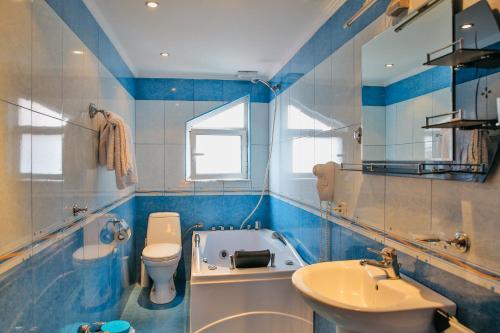 een badkamer met een bad, een toilet en een wastafel bij Gold Hotel in Korçë
