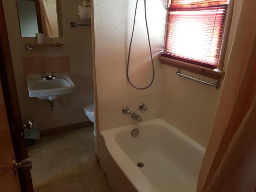 La salle de bains est pourvue d'une baignoire et d'un lavabo. dans l'établissement Hat Motel, à Medicine Hat