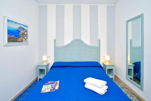 a blue bed in a white room with two mirrors at Charme Hotel La Villa Tina in Ischia