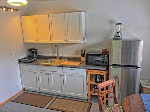 a kitchen with white cabinets and a stainless steel refrigerator at Hale “Hā Hā” in Pahoa