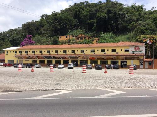 a building with cars parked in a parking lot at Pousada Catavento in Piraí