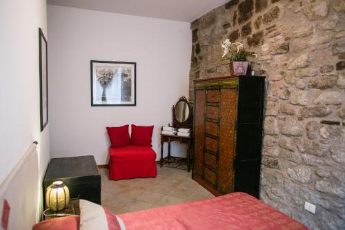 a room with a red chair and a stone wall at B&B Orchard in Viterbo