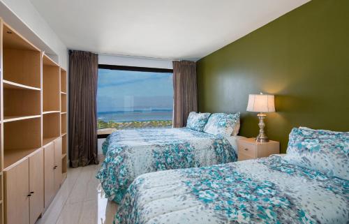a bedroom with two beds and a window with the ocean at Signature Suites 11 in Honolulu