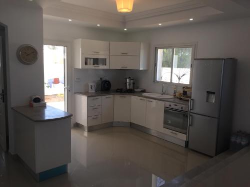 a kitchen with white cabinets and a stainless steel refrigerator at Belle Villa Avec Piscine sans vis a vis in Midoun