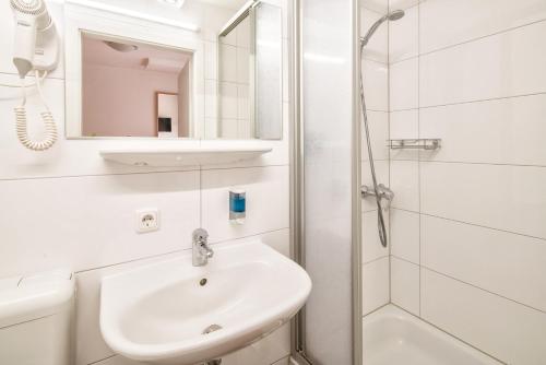 a white bathroom with a sink and a shower at Hotel Bettstadl in Landshut