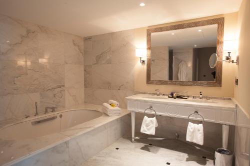 La salle de bains est pourvue d'une baignoire, d'un lavabo et d'un miroir. dans l'établissement Palm Camayenne, à Conakry