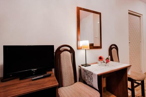 a hotel room with a television and a table and chairs at Hotel Galicja in Ulanów