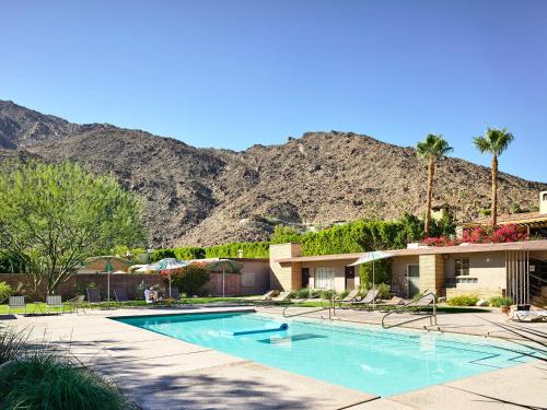 a swimming pool in front of a resort with mountains at The Hideaway - 21 and Over in Palm Springs