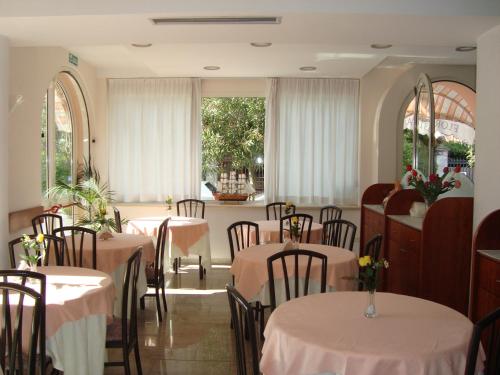 a dining room with tables and chairs and windows at Florentia Hotel in Lido di Camaiore