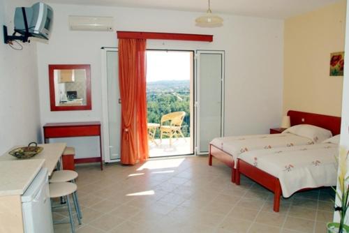 a bedroom with two beds and a kitchen and a balcony at Alkioni Studios in Trapezaki