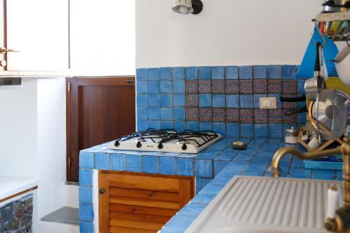 a blue tiled kitchen with a stove and a sink at La Casa del Pescatore in Filicudi
