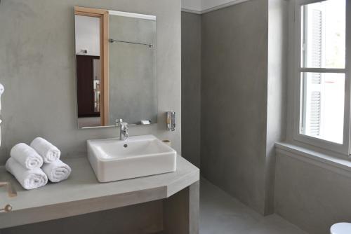 a bathroom with a sink and a mirror and towels at Douskos Guesthouse in Hydra