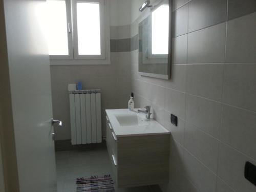 uma casa de banho branca com um lavatório e um espelho em San Teodoro Apartment em Mestre