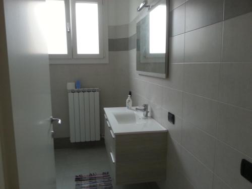 un bagno bianco con lavandino e specchio di San Teodoro Apartment a Mestre