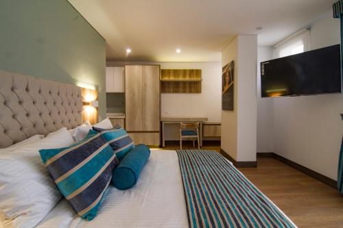 a bedroom with a bed with two pillows and a television at De Película Hotel in Bogotá