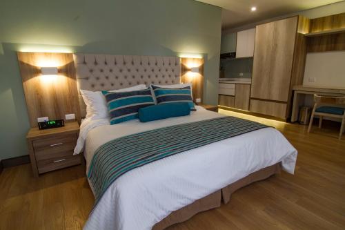 a large bedroom with a large bed with blue pillows at De Película Hotel in Bogotá