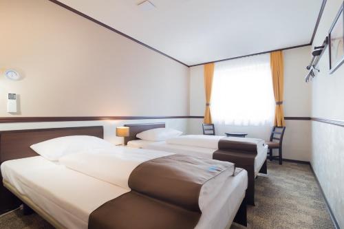 a hotel room with two beds and a window at Toyoko Inn Frankfurt am Main Hauptbahnhof in Frankfurt/Main