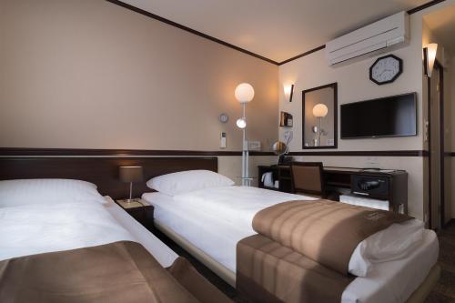 a hotel room with two beds and a flat screen tv at Toyoko Inn Frankfurt am Main Hauptbahnhof in Frankfurt