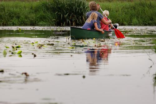 a man and woman and child in a canoe on a lake at Landhuis Hotel Rikus in Eext