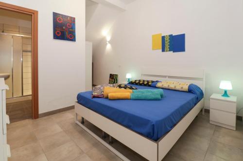 ドンナルカータにあるLa Casa di Marioのベッドルーム1室(青いシーツとカラフルな枕が備わるベッド1台付)