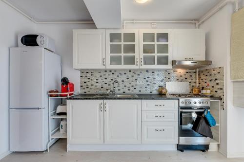 a white kitchen with white cabinets and a sink at Bucharest Airport Suites & Villas in Otopeni